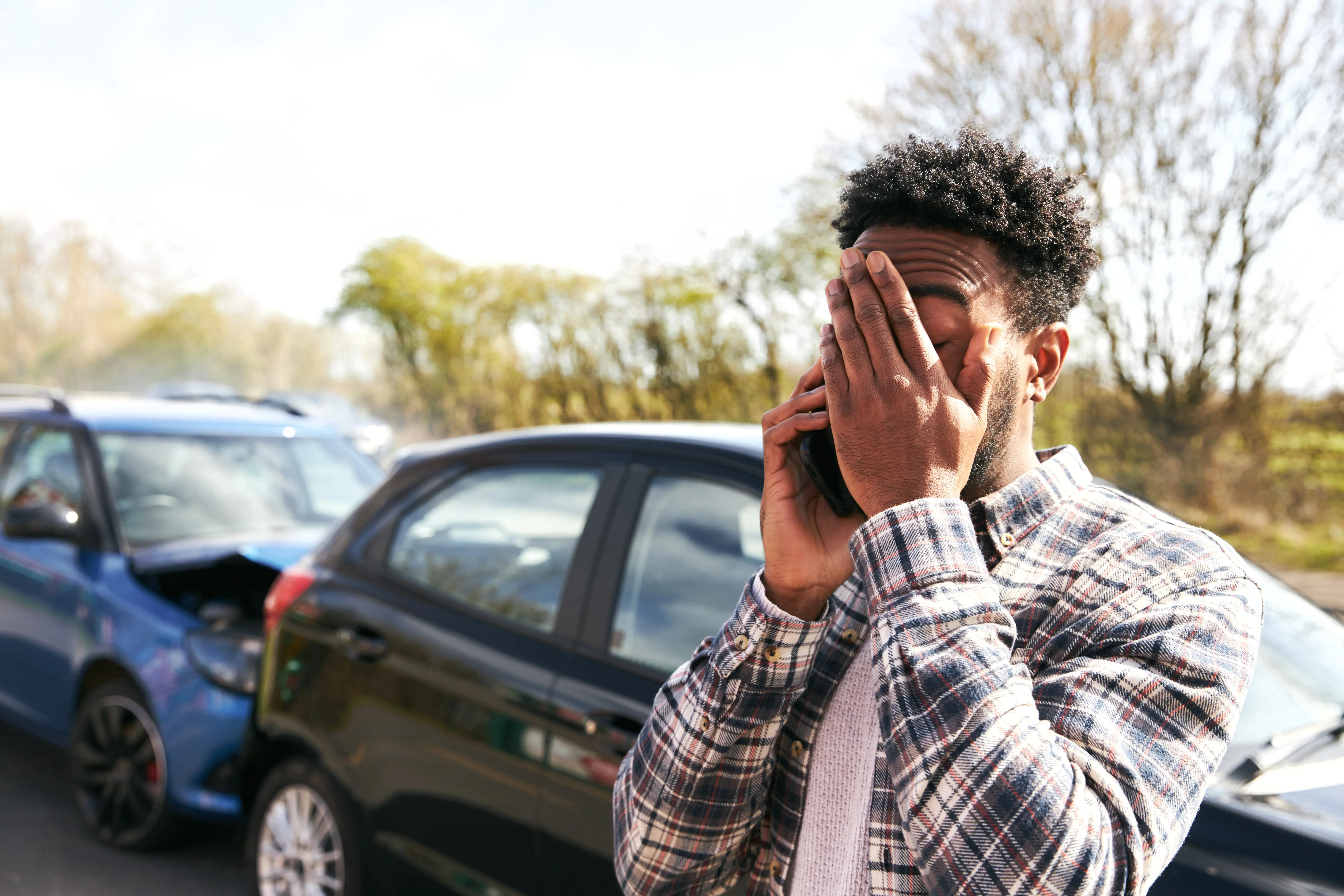 A male driver on the phone after an at fault car accident wondering what to do after the accident that was his fault.