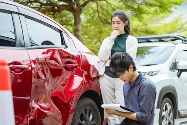 A couple looking at the damage to their electric vehicle and considering how to choose their repairer.