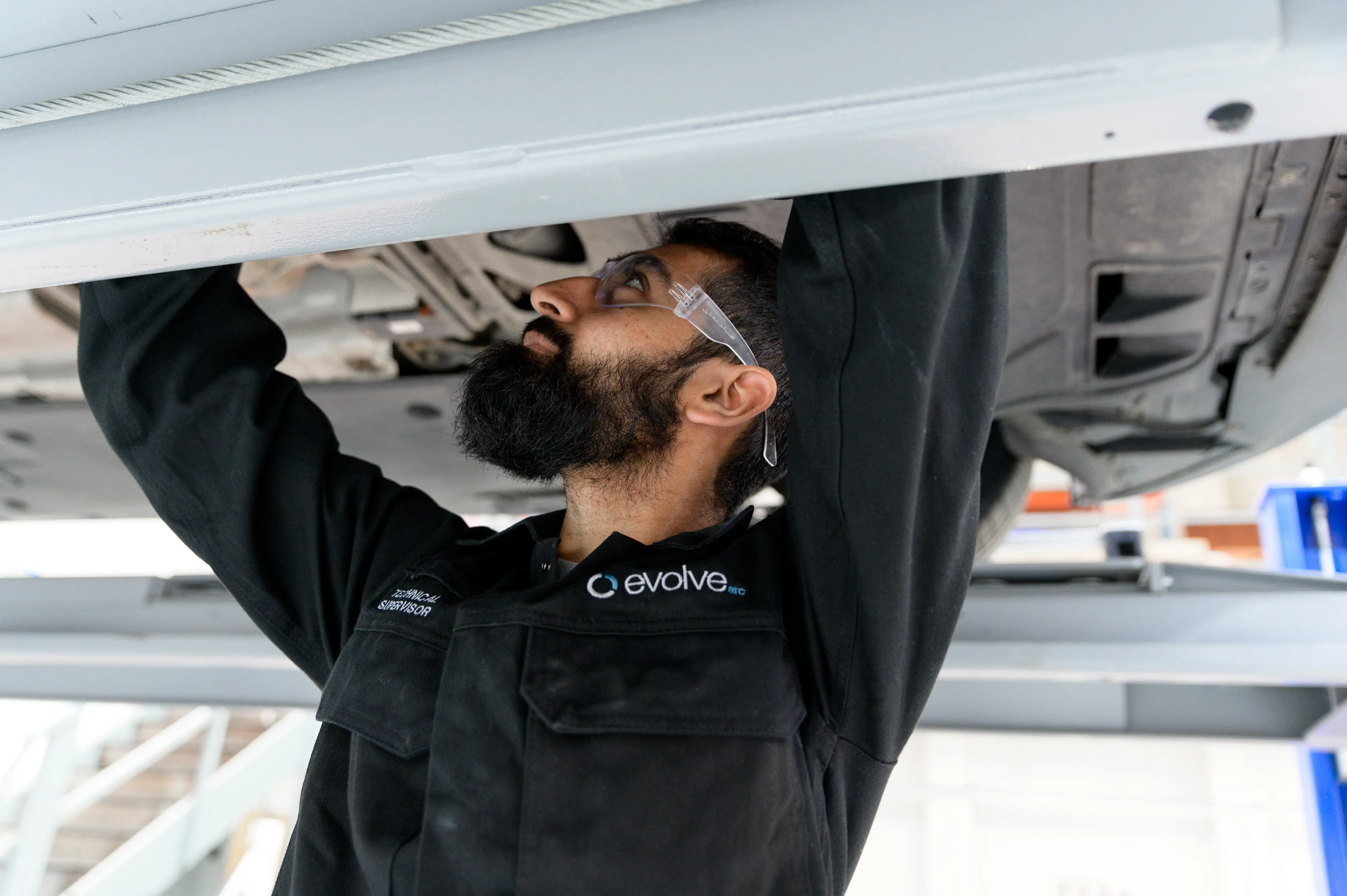 A mechanic in uniform working underneath a car which is part of Evolve Arc’s car accident management services.